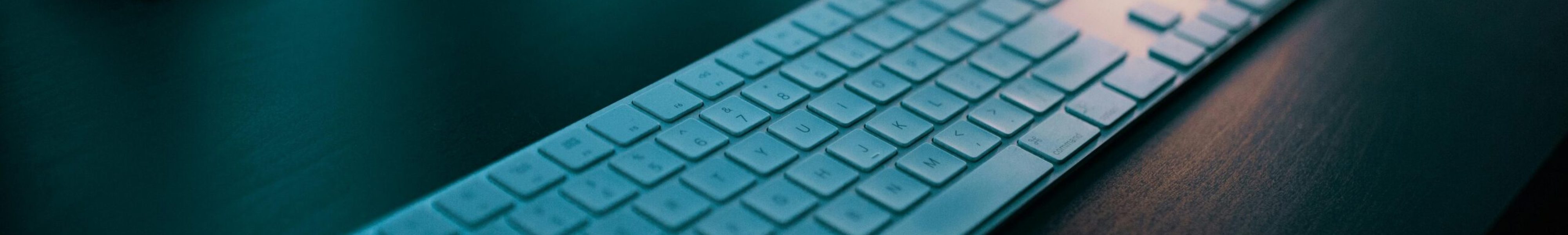 A modern wireless keyboard placed on a sleek desk, illuminated by ambient lighting in a tech-savvy office setting.